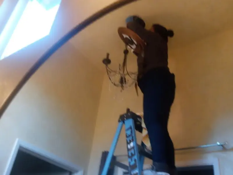 Electrician installing a chandelier in a Netcong residence